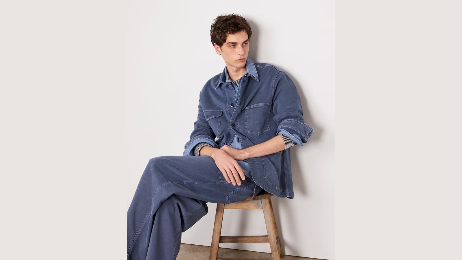 Homme assis en surchemise et pantalon de toile bleue Officine Générale