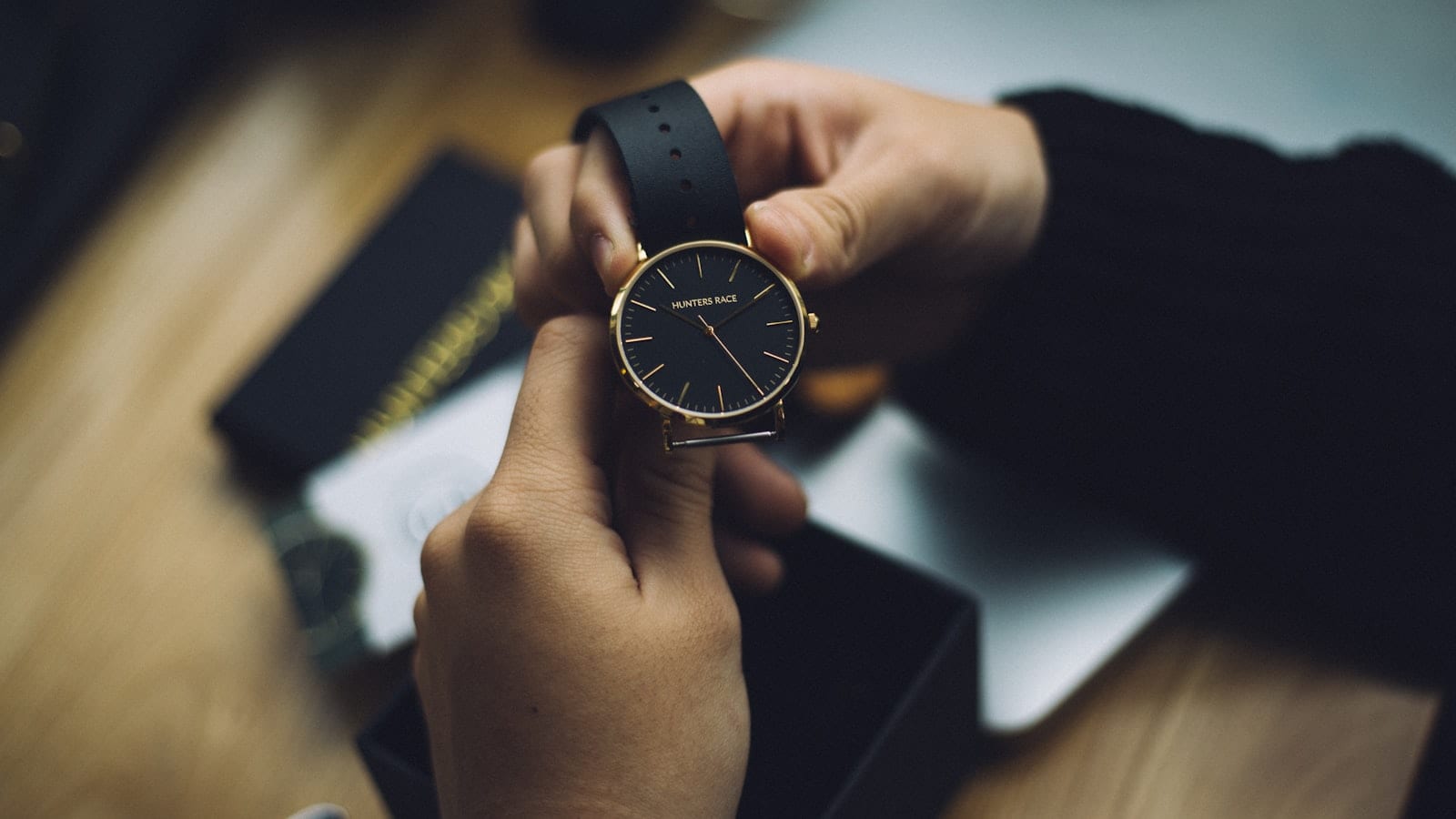 Montre acier posée sur un bureau à côté de sa boîte, de ses papiers de garantie et d'une loupe d'horloger