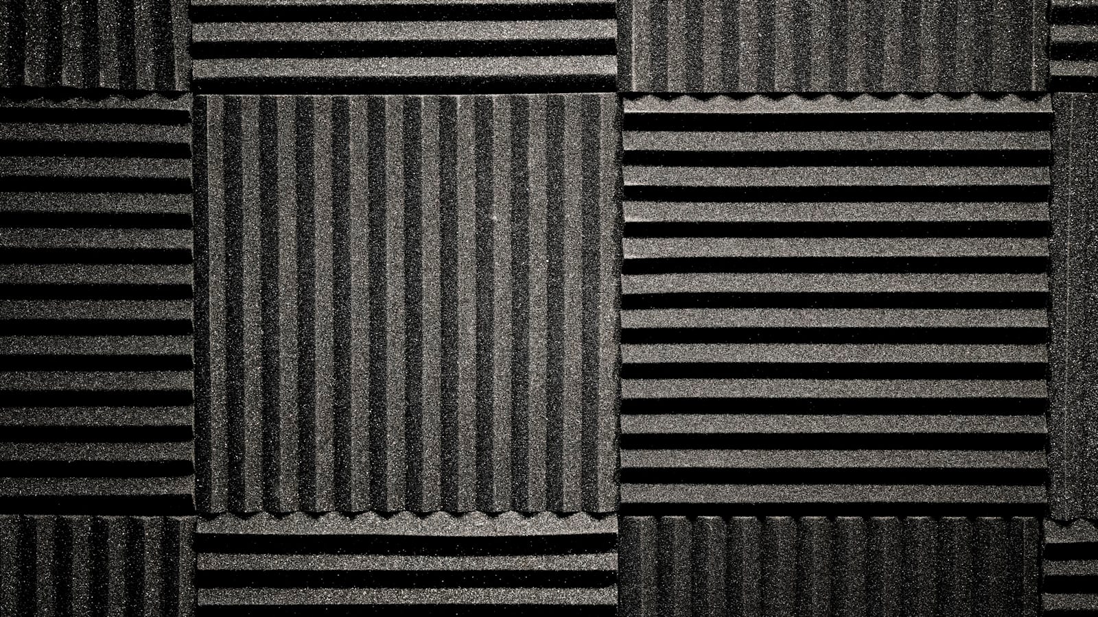Bureau de douze metres carres avec panneaux absorbants sur le mur lateral, rideau epais devant la fenetre et tapis a poils longs sous le siege