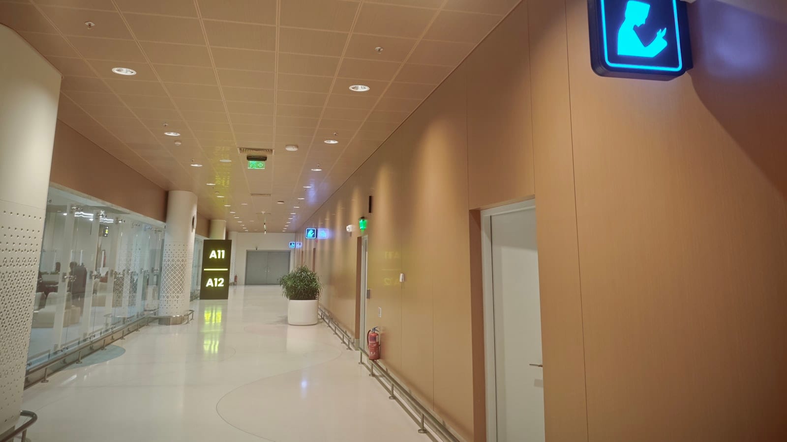 Passagers marchant dans un couloir de correspondance vitré, panneau indiquant la direction des portes B et C