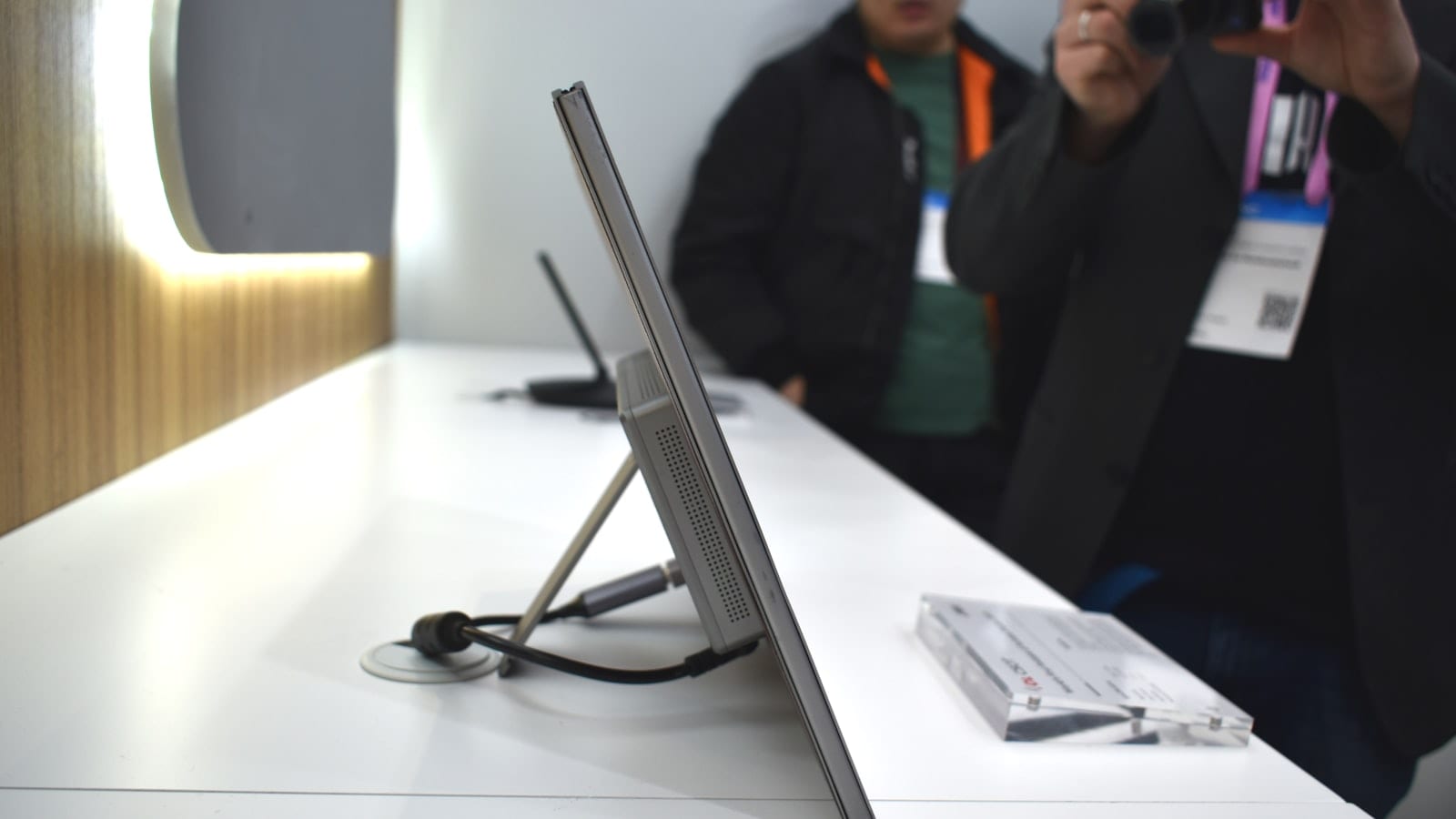 Ordinateur portable relié par un câble USB-C à un second écran fin posé sur un bureau étroit de chambre d'hôtel, avec un tableur affiché sur les deux dalles.