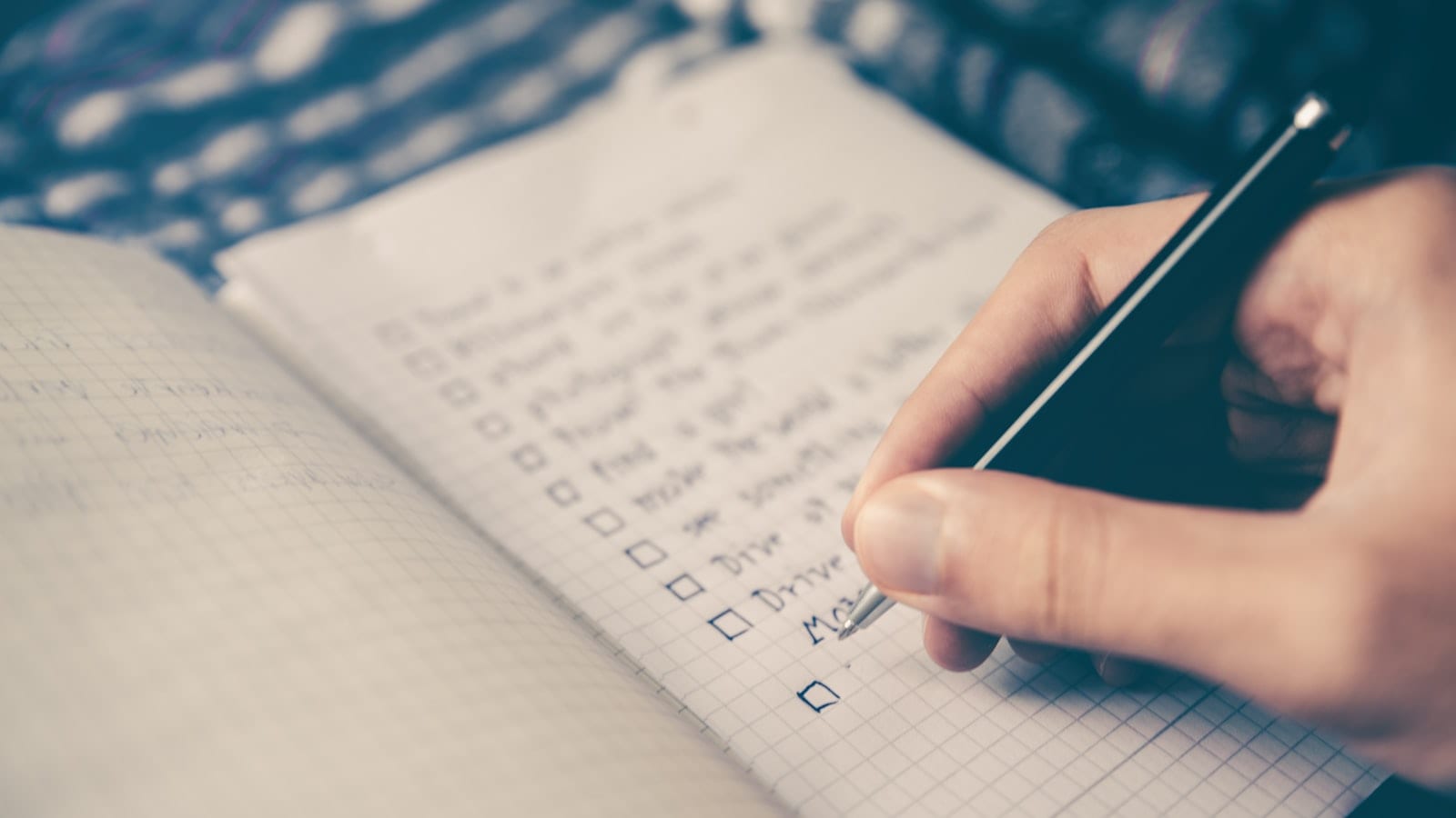 Bureau vu de dessus avec un téléphone affichant une liste de tâches, un ordinateur portable ouvert sur un tableau de projets, un carnet annoté et un stylo posé en travers.