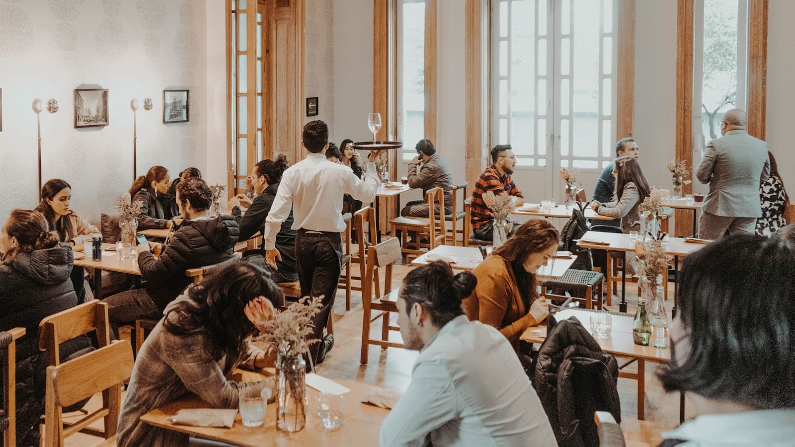 Salle de restaurant au plafond haut en béton, tables serrées, un sonomètre posé sur une nappe blanche