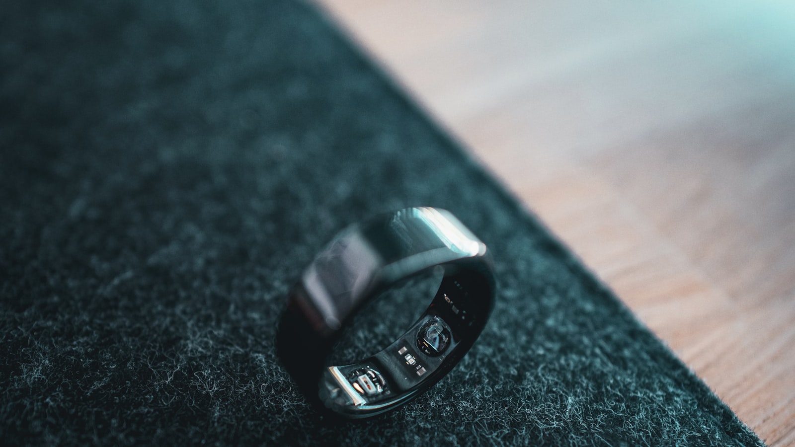 Oura Ring 5 posée sur son chargeur à côté d'un passeport