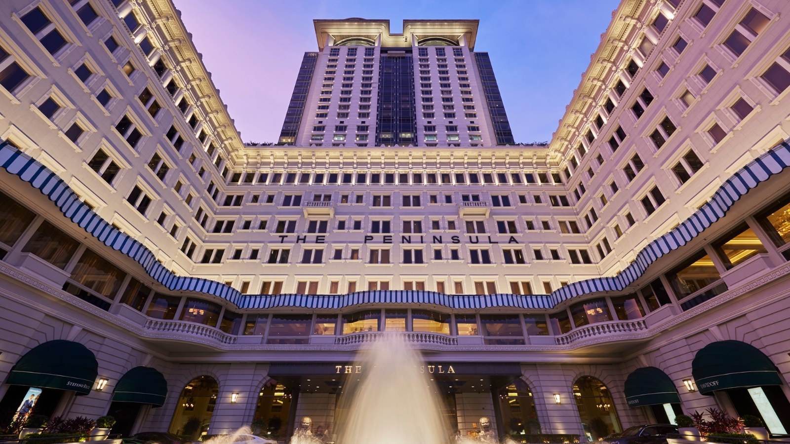 Cour interieure du Peninsula Hong Kong a la tombee du jour, la tour de 1994 eclairee au-dessus de la maison de 1928