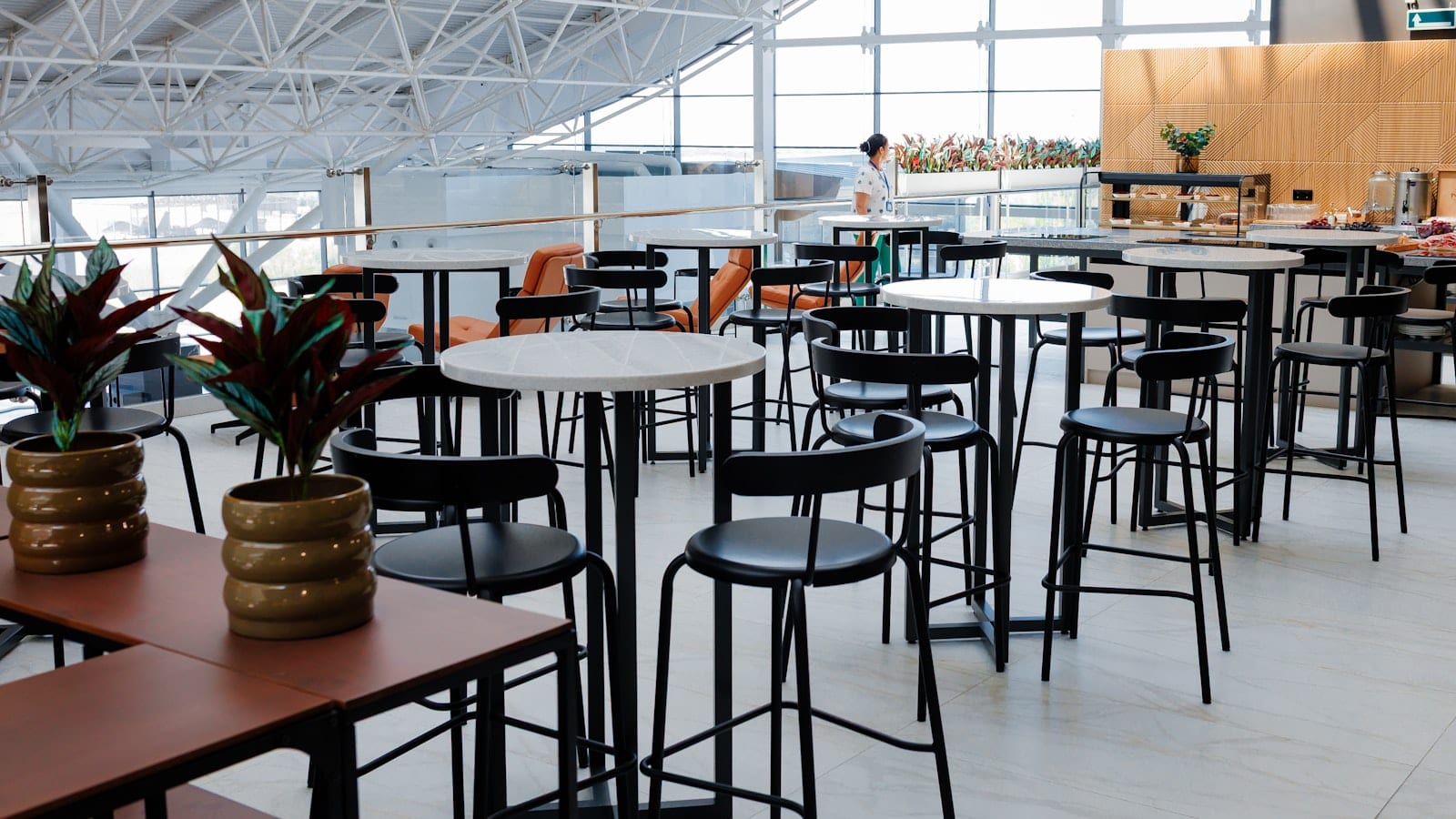 Salon d'aéroport avec fauteuils individuels, prises électriques encastrées et vue sur le tarmac au crépuscule