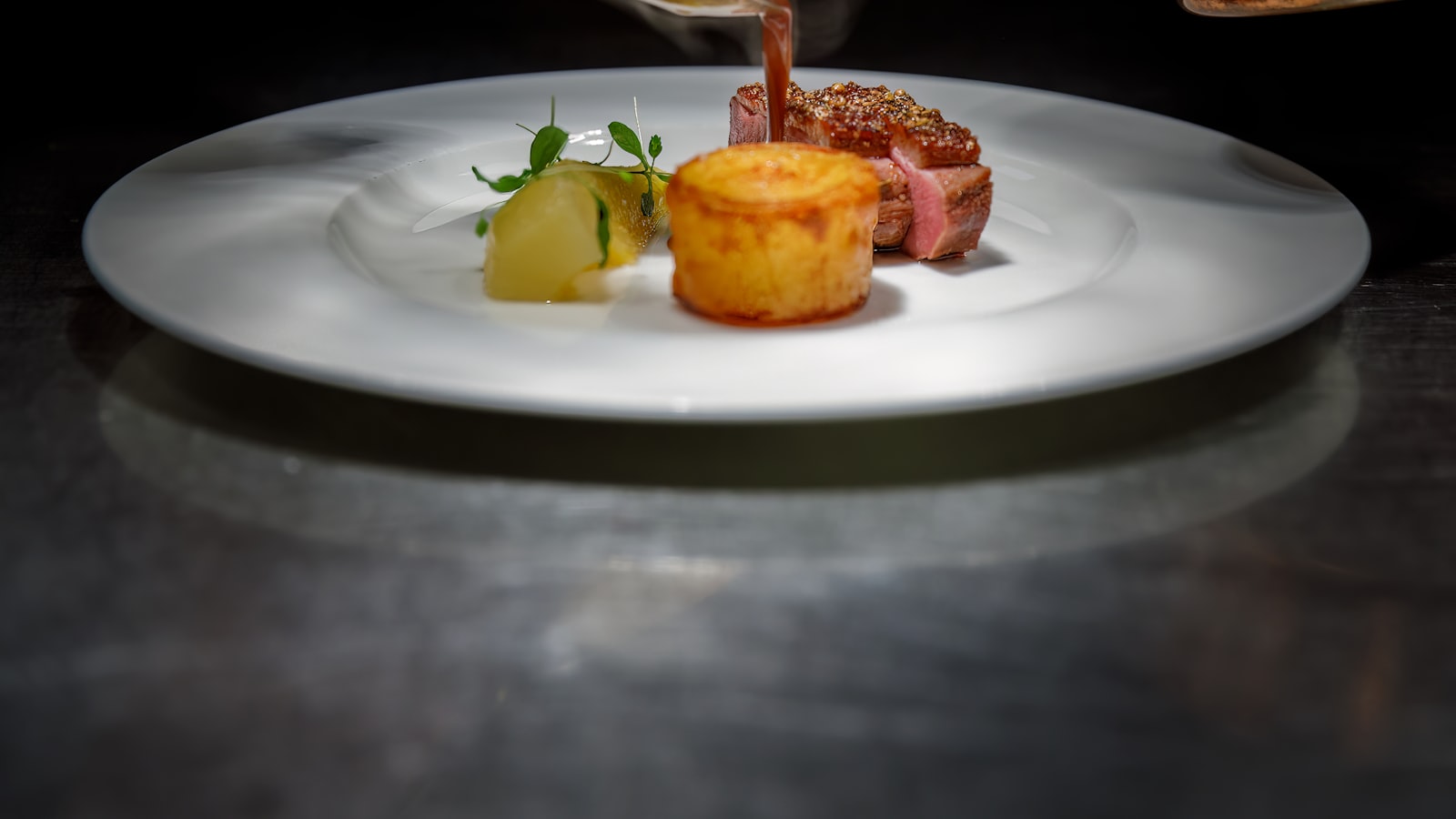 Salle de restaurant en fin de service de midi, tables dressées avec nappes blanches, un téléphone fixe posé sur le pupitre d'accueil